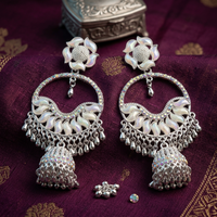 Silver earrings with floral designs on a purple fabric background