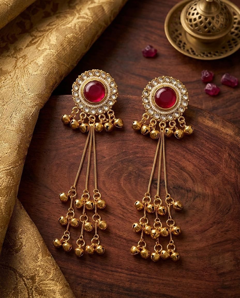 Gold earrings with red gemstones on a wooden surface