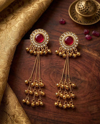 Gold earrings with red gemstones on a wooden surface