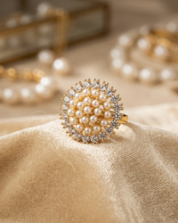 Gold ring with pearl embellishments on a beige fabric background
