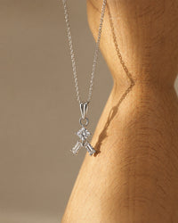 Silver necklace with a diamond pendant on a wooden mannequin.