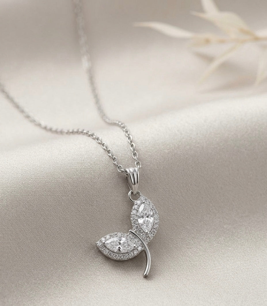 Silver necklace with a leaf-shaped pendant on a light fabric background