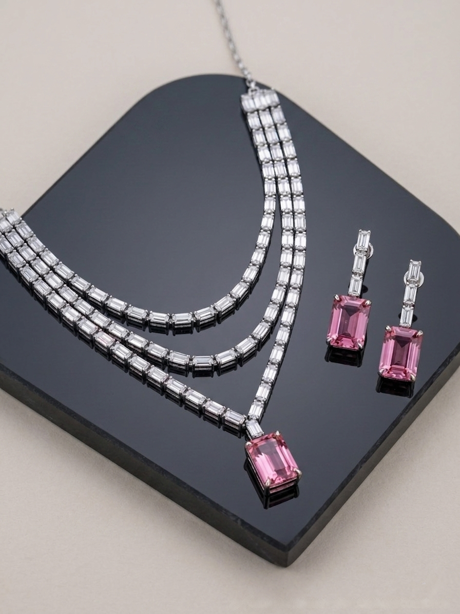 Jewelry set with pink gemstone earrings and necklace on a black stand.