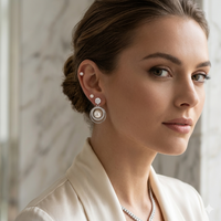 Woman wearing pearl earrings and a necklace with a neutral background