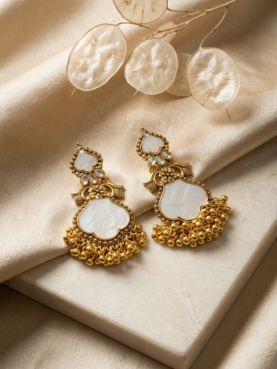 Goldden earrings with white stones on a beige fabric background