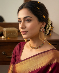 Woman wearing traditional jewelry and a saree with a blurred background