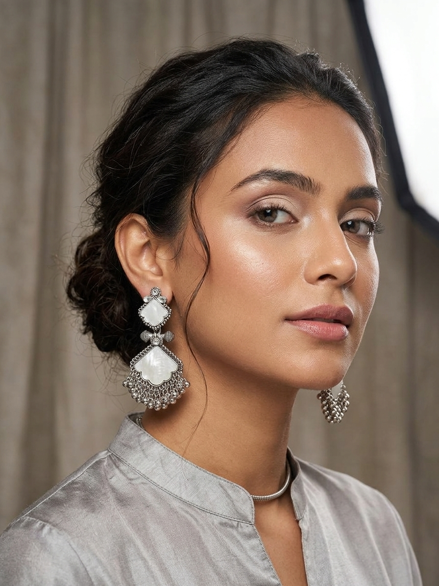 Woman wearing large, ornate earrings against a neutral background