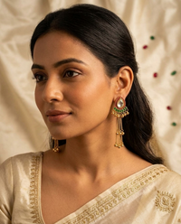 Woman wearing traditional earrings and a saree with a neutral background