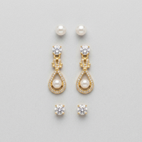 Gold earrings with pearls and crystals on a light gray background