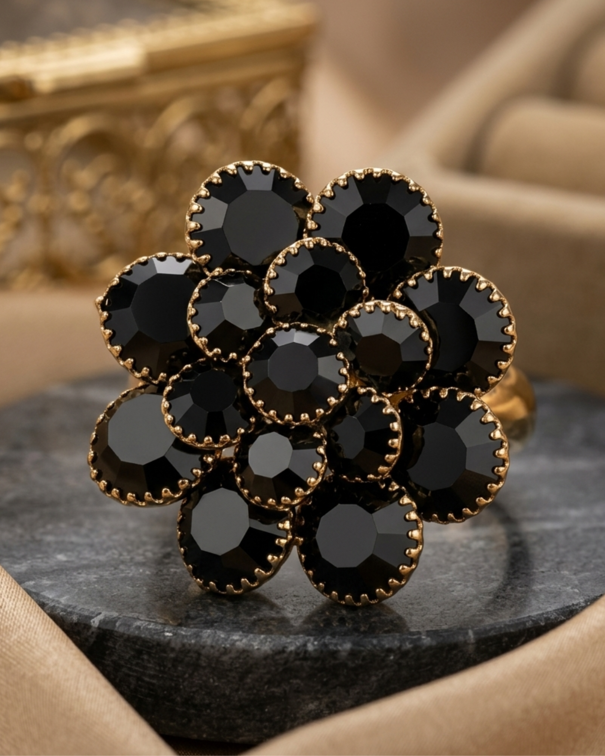 Black gemstone ring with gold setting on a dark surface