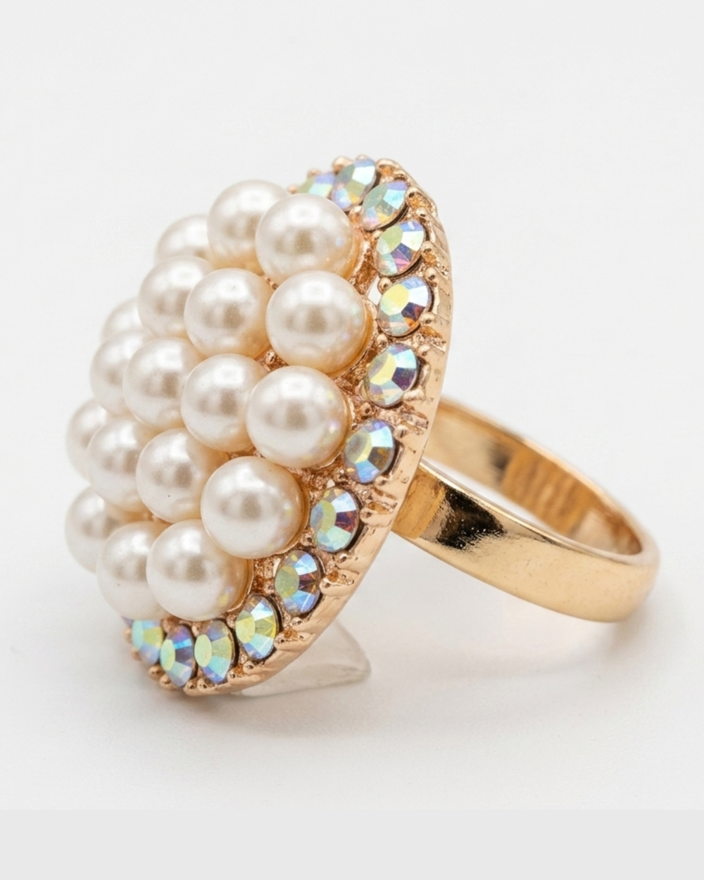 Gold ring with pearls and rhinestones on a white background