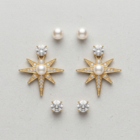 Gold star-shaped earrings with pearls and clear stones on a light gray background