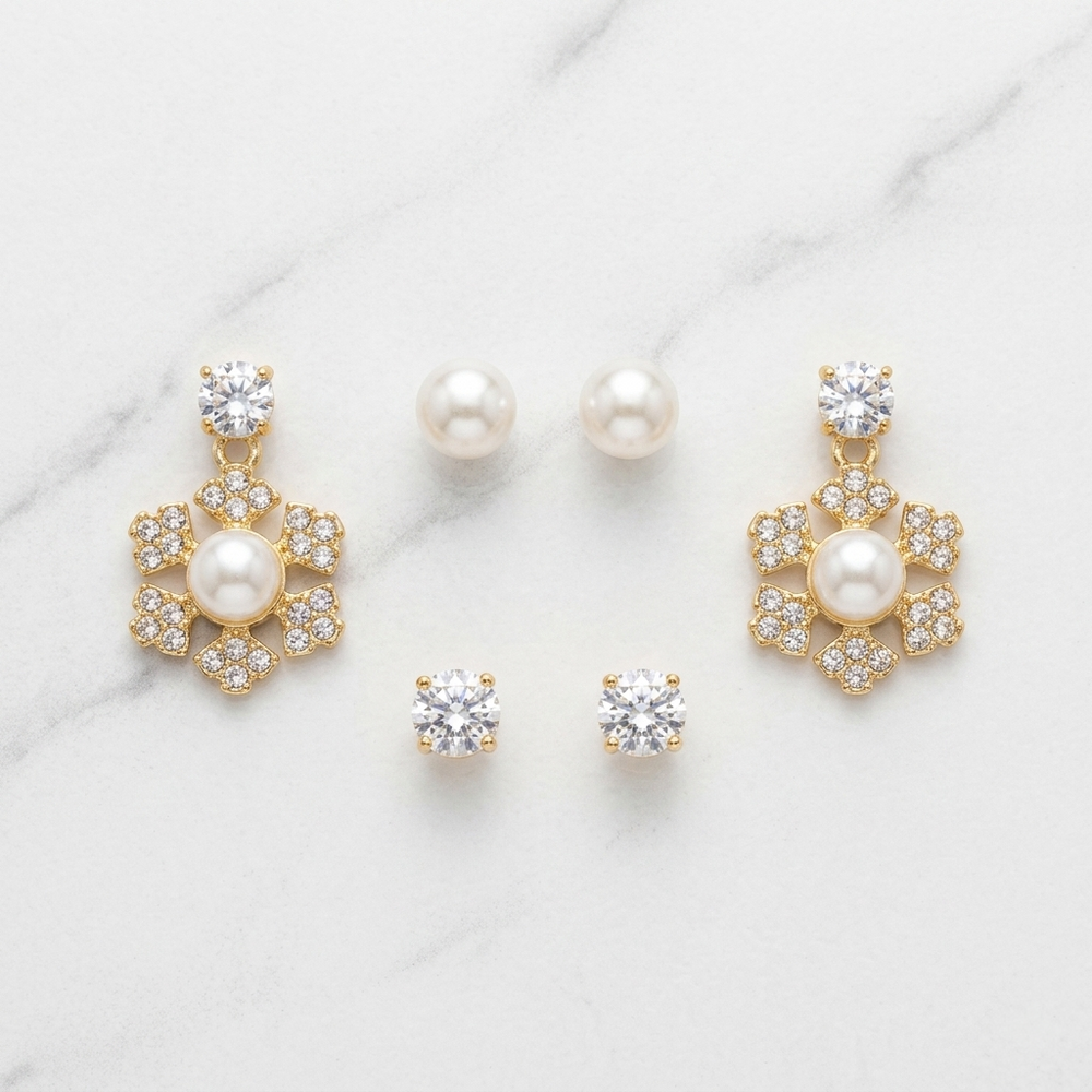 Set of gold and pearl earrings on a marble surface