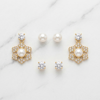 Set of gold and pearl earrings on a marble surface