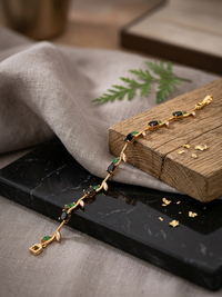 Gold bracelet with green gemstones on a wooden block with a natural background