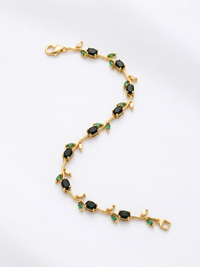 Gold bracelet with green gemstones on a white background