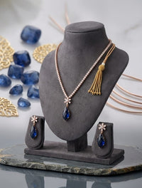 Jewelry set with necklace and earrings on a gray stand, surrounded by blue stones and gold accents.