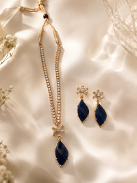 Jewelry set with blue teardrop pendants on a neutral background