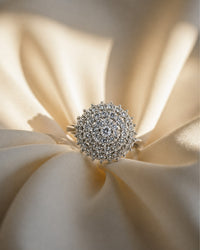 Silver ring with intricate design on a cream fabric background