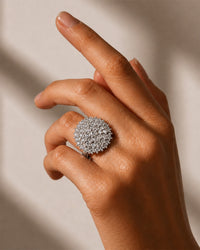 Hand wearing a silver textured ring on a neutral background