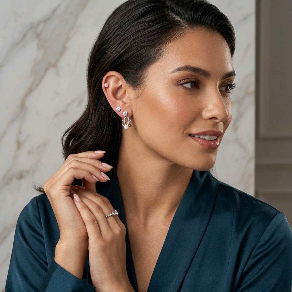 Woman wearing earrings and a ring, with a neutral background