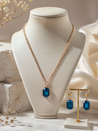 Necklace with blue pendant on a mannequin bust and matching earrings on a stand.