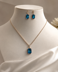 Jewelry set with blue gemstone necklace and earrings on a mannequin.