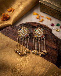 Pair of gold earrings with gemstones on a textured surface