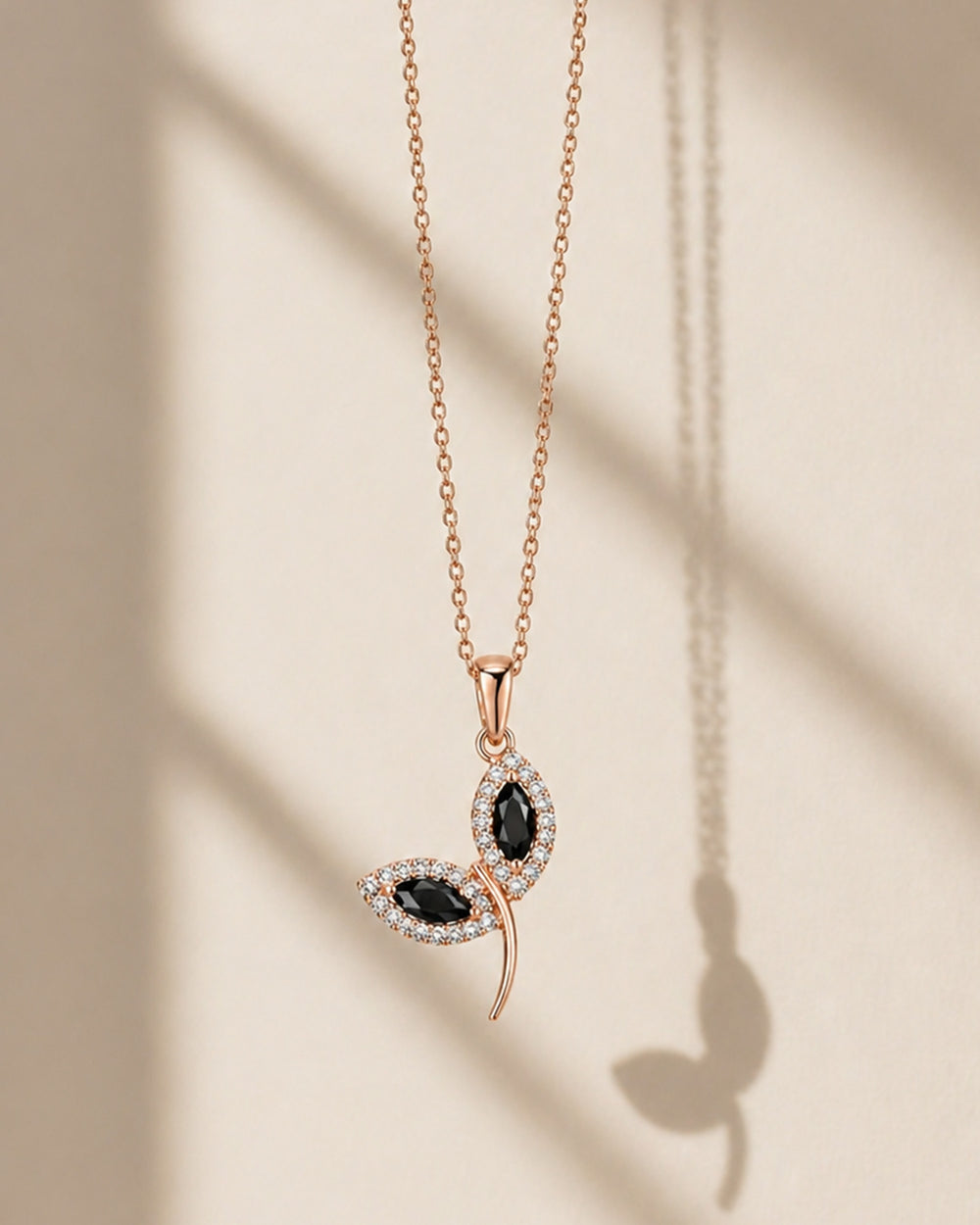 Rose gold necklace with black gemstones on a beige background