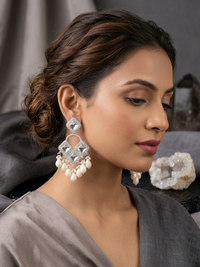 Woman wearing large, ornate earrings with a neutral background